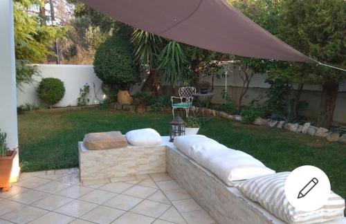 a patio with a couch and an umbrella in a yard at Casa Martina 2 (Spata) 10min El.Venizelos airport. in Spata