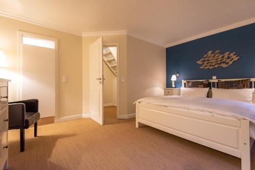a bedroom with a white bed and a blue wall at Bens Hüs in Braderup