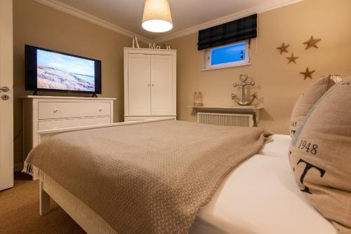 a bedroom with a bed and a flat screen tv at Bens Hüs in Braderup