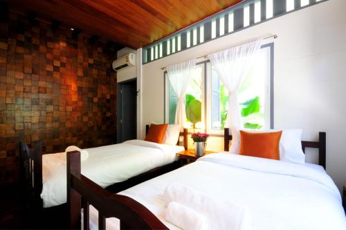 a bedroom with two beds and a window at Baan Noppawong in Bangkok