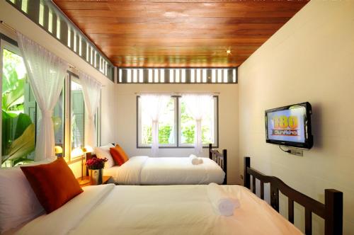 a bedroom with two beds and a flat screen tv at Baan Noppawong in Bangkok