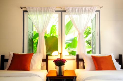 a bedroom with two beds and a window at Baan Noppawong in Bangkok