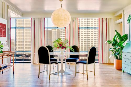 a dining room with a table and chairs and windows at Virgin Hotels New Orleans in New Orleans