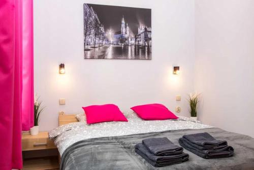 a bedroom with a bed with pink pillows on it at Koletek st Apartment in Krakow