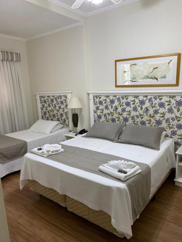 a bedroom with two beds and a painting on the wall at Hotel Da Vinci in Serra Negra