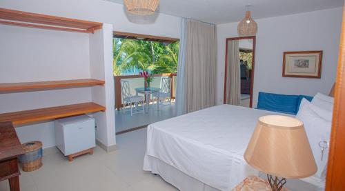 a bedroom with a bed and a balcony with a table at Arraial Bangalô Praia Hotel in Arraial d'Ajuda