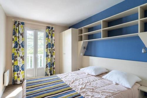 a bedroom with a large bed with a blue wall at Maison sur golf avec piscine chauffée à Lacanau Océan in Lacanau