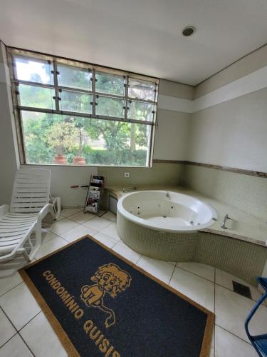 a bathroom with a bath tub and a large window at Condomínio Resort na cidade das águas sulfurosas in Poços de Caldas