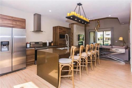 a kitchen with a stainless steel refrigerator and a bar with stools at Magic Village 4 Bedroom! Welcome Home! in Orlando