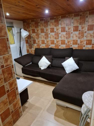 a living room with a black couch and a brick wall at Casa Sofía in Murcia