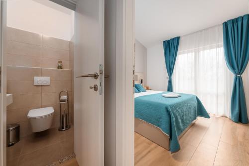een slaapkamer met een bed, een toilet en blauwe gordijnen bij Apartments Grota in Poreč