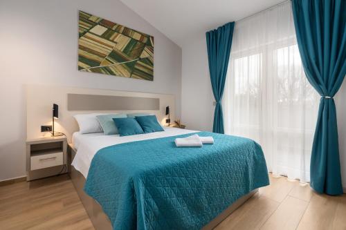 een slaapkamer met een bed met een blauwe deken en een raam bij Apartments Grota in Poreč