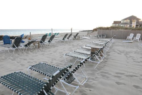 - une rangée de chaises longues et de tables sur la plage dans l'établissement By The Sea Guests Bed & Breakfast and Suites, à Dennis Port