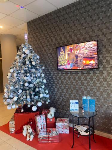a christmas tree in a room with presents and a tv at Eracle Hotel in Volla