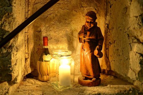 a statue of a man standing next to a candle and a bottle at Hotel Restaurant DAS RÖSSL in Windischgarsten