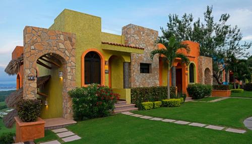 a house with a green lawn in front of it at El Corazón Golf & Spa Resort Manzanillo in Manzanillo