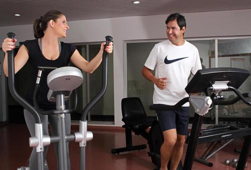 a man and a woman exercising on treadles in a gym at Hotel Majestic in Águas de Lindóia