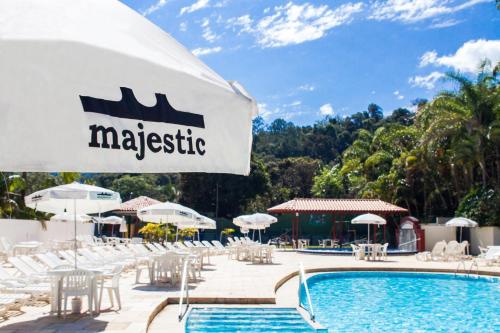 a swimming pool with white chairs and umbrellas at Hotel Majestic in Águas de Lindóia