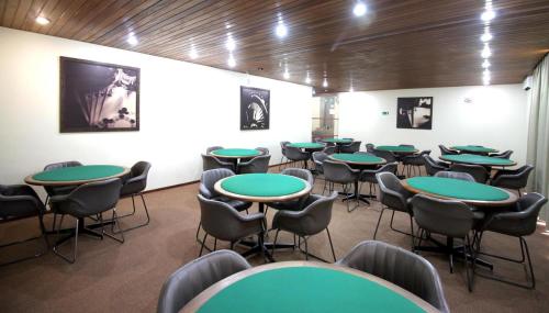 a room with green tables and chairs in it at Hotel Majestic in Águas de Lindóia