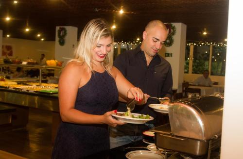a man and a woman preparing food in a kitchen at Hotel Majestic in Águas de Lindóia