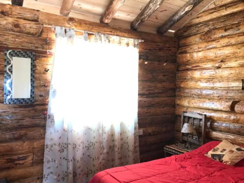 a bedroom in a log cabin with a red bed at ALIWWE in Uspallata
