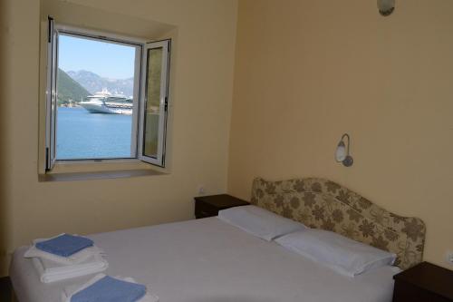1 dormitorio con 1 cama y una ventana con un barco en el agua en Apartments Ivanovic, en Kotor