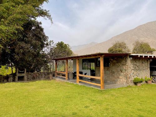 una casa de piedra con porche en un campo en Las Cabañas de Incahuasi en Lunahuaná