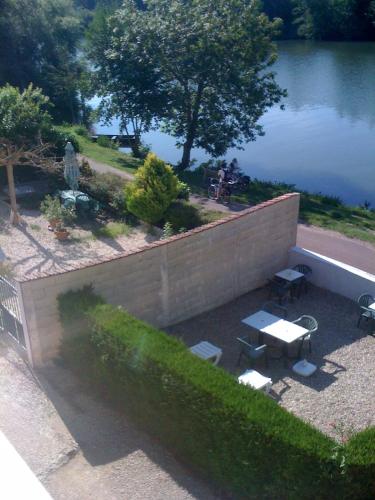 un mur de retenue avec une table et des bancs à côté d'un lac dans l'établissement La Berge Meublé de tourisme 2 étoiles, à Laroche-Saint-Cydroine
