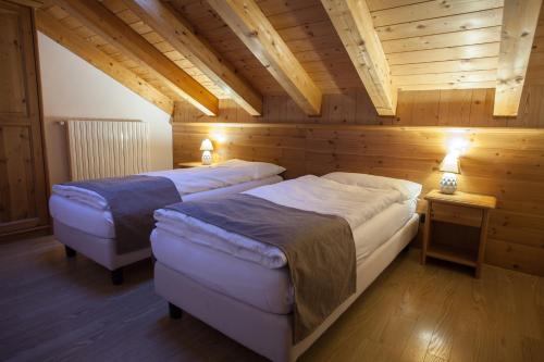 two beds in a room with wooden walls at lareit appartamenti in Bormio