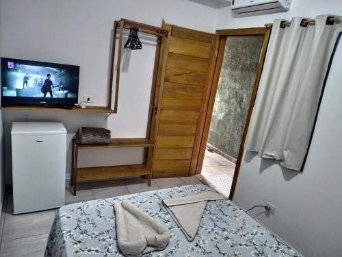 a room with a bed and a television and a door at Pousada Na Praia Ubatuba in Ubatuba