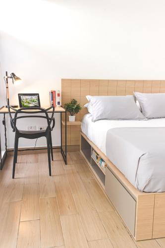 een slaapkamer met een bed en een bureau met een laptop bij 80Cooliving Medellín in Medellín
