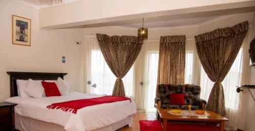 a bedroom with a large white bed and windows at The Haven Guest House in Mbabane