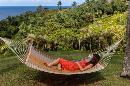 a woman in a red dress laying in a hammock at The Cliffs at Princeville in Princeville