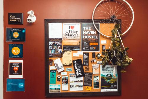 a bulletin board with posters on a wall at The Haven Hostel in Thunder Bay