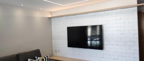 a flat screen tv mounted on a white brick wall at Itacimirim Apartments Ondas in Itacimirim