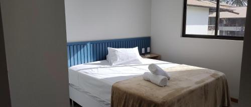 a bedroom with a white bed with a blue headboard at Itacimirim Apartments Ondas in Itacimirim