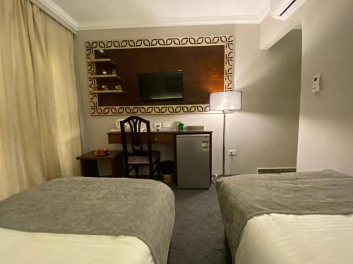 a hotel room with two beds and a desk at Khan Duidar Inn - Pyramids View Rooftop in Cairo