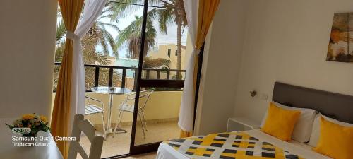 a bedroom with a bed and a balcony with a table at Aparthotel Santa Maria Beach in Santa Maria