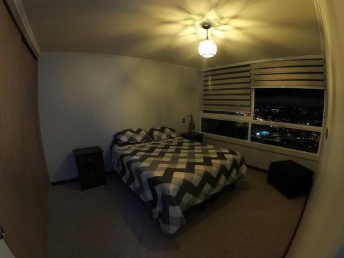 a bedroom with a bed and a window with a city at Departamento Coquimbo La Serena in Coquimbo