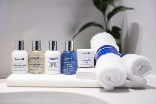 a bathroom counter with several bottles of moisturizers and towels at Radisson Blu Resort Visakhapatnam in Visakhapatnam
