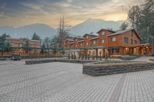 a large building with mountains in the background at Radisson Golf Resort Pahalgam in Pahalgām