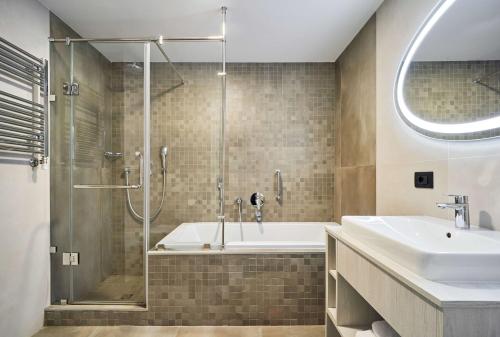 a bathroom with a shower and a tub and a sink at Radisson Hotel City Centre Odesa in Odesa