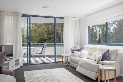 a living room with a white couch and a tv at 123 Landmark in Nelson Bay