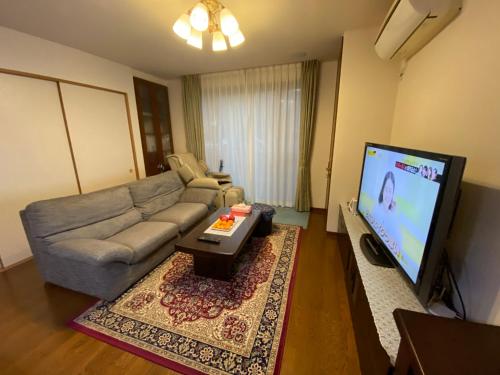 a living room with a couch and a flat screen tv at 花沢民宿 in Odawara