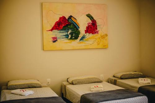 a room with two beds and a painting on the wall at Rancho Garcinha - Lago de Furnas in São José da Barra