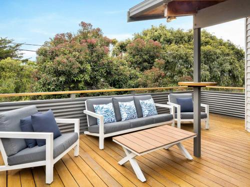 a deck with couches and a coffee table on a balcony at Sandy Feet Retreat in Cape Woolamai