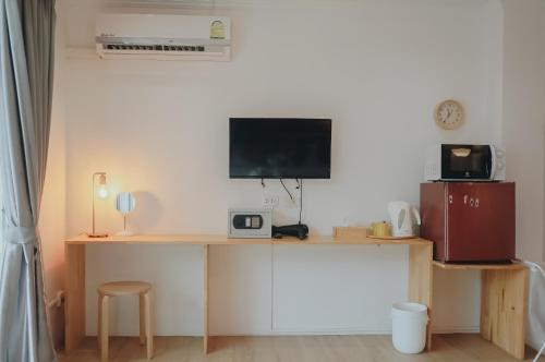 Habitación con escritorio y TV en la pared. en Thira House, en Karon Beach