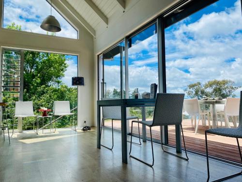 a dining room with a table and chairs and large windows at Acacia Cliffs Lodge in Taupo