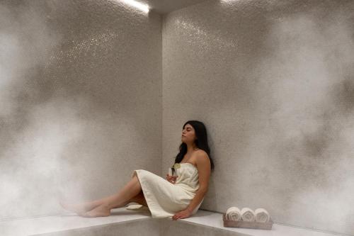 a woman in a white dress sitting on a wall at Warwick Melrose Hotel in Dallas