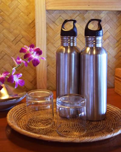 two metal water bottles and two glasses on a table at The Narima - SHA Plus in Ko Lanta